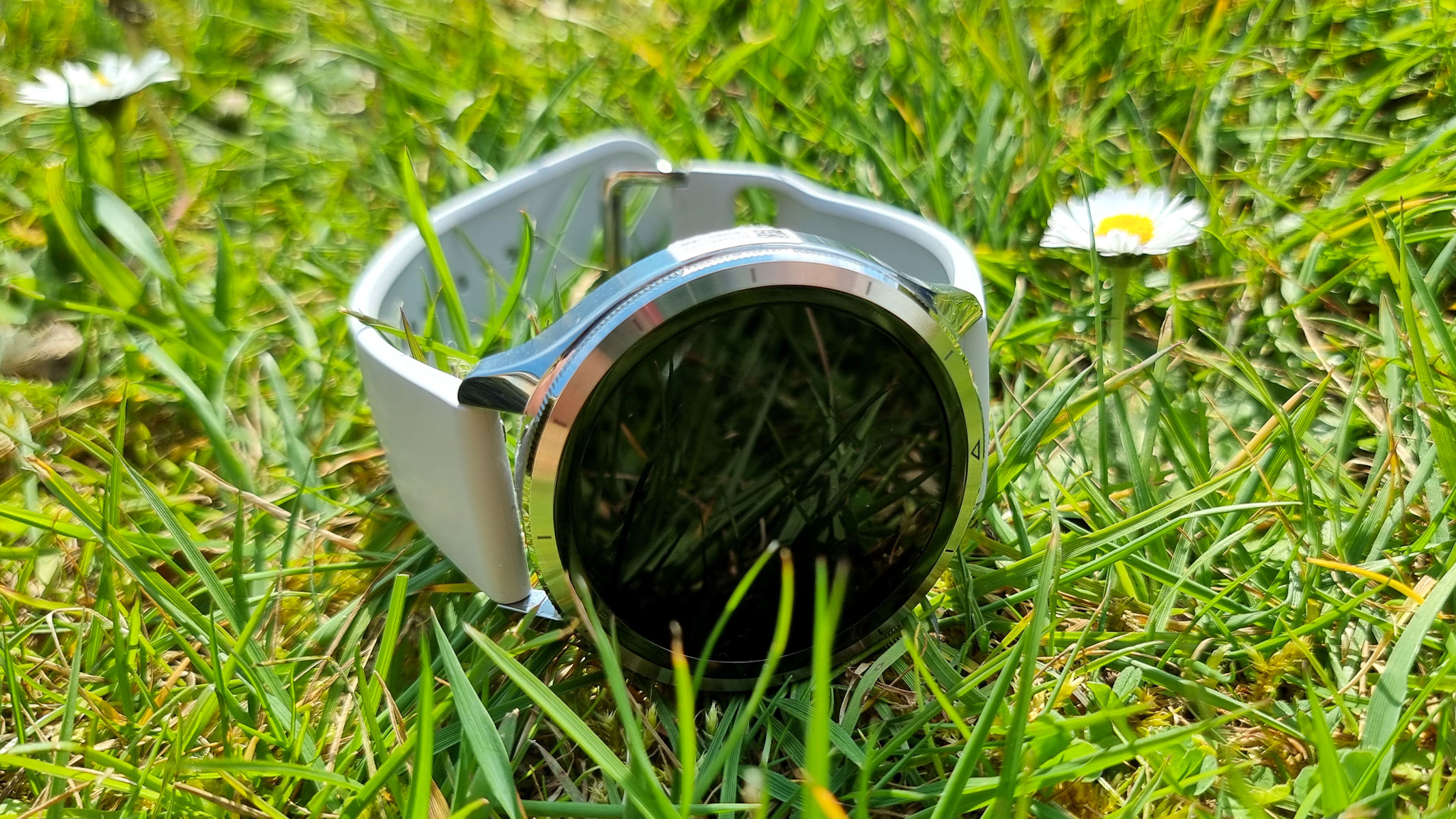 The Xiaomi Watch S4 laying sideways on the grass