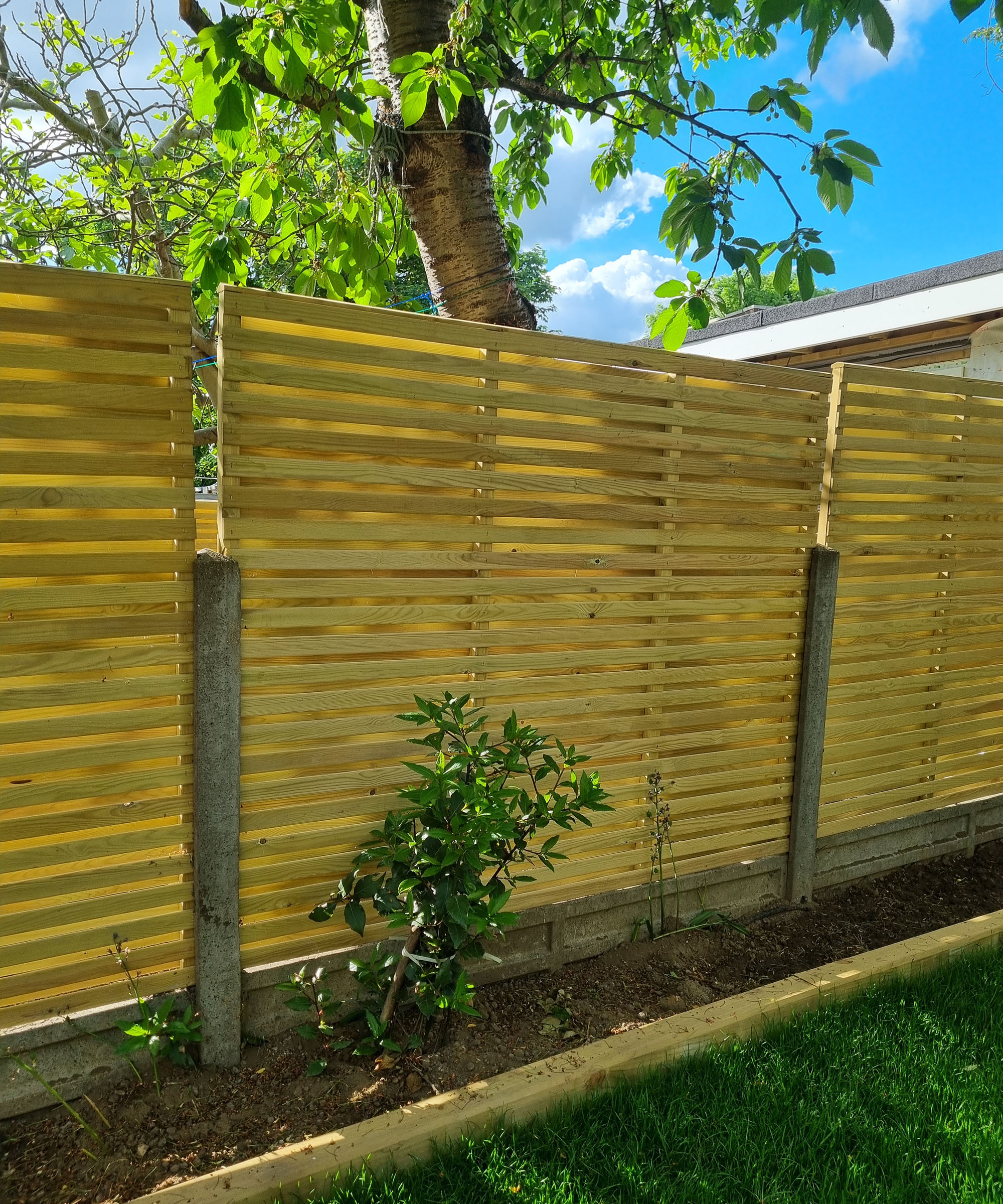 A horizontal slatted wooden fence with concrete posts