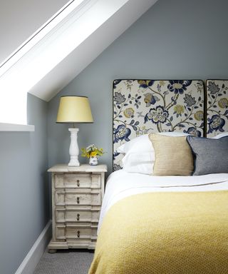 A bed with a floral headboard and a yellow throw