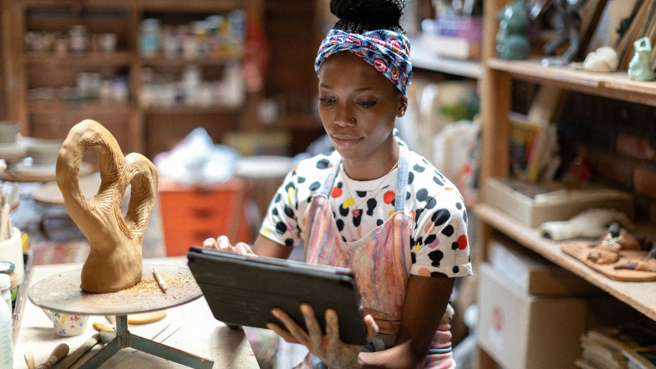 A woman sits using her tech for craft