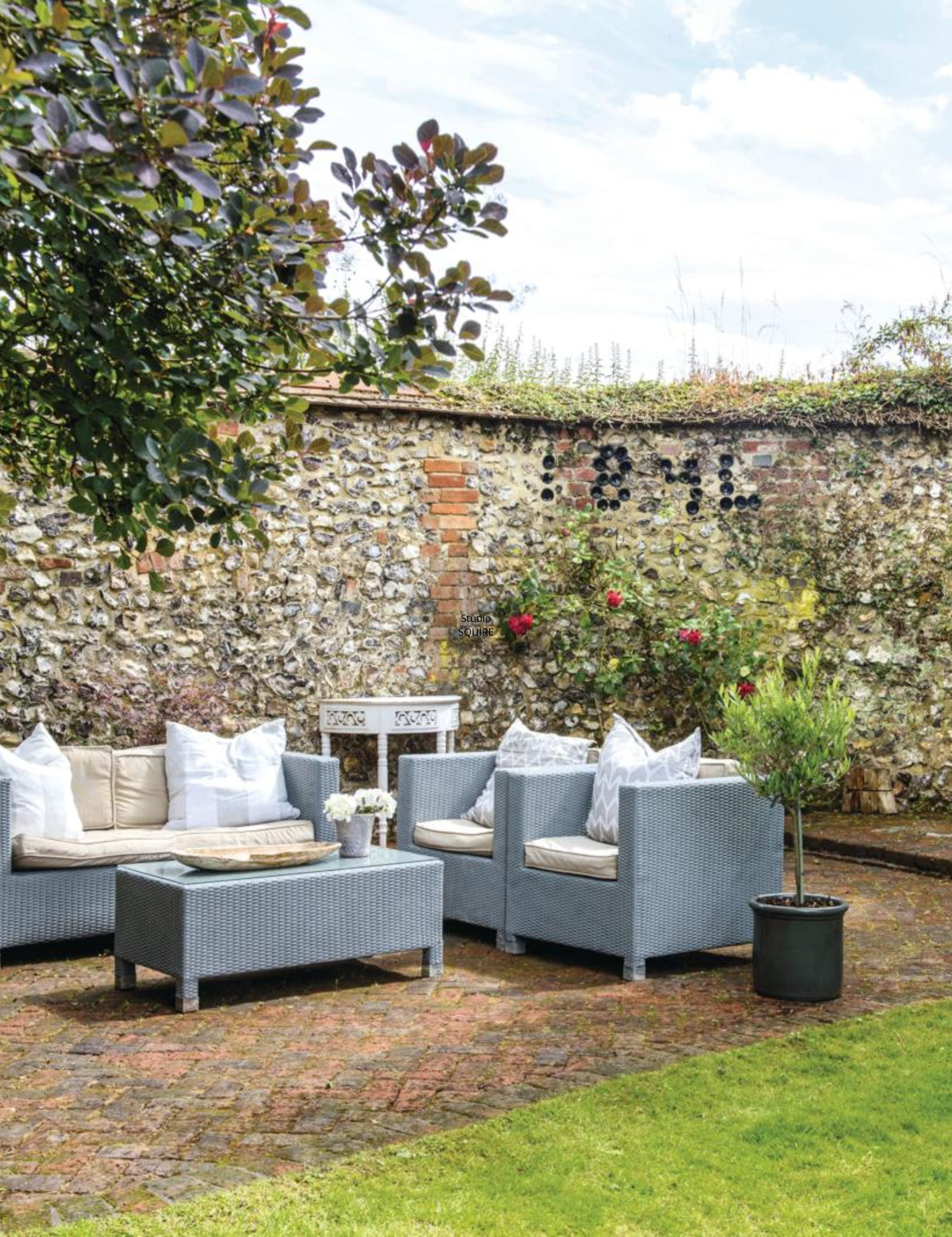 Charming brick garden patio featuring a woven wicker seating group