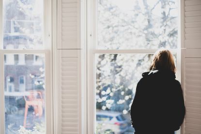 A woman looking out of a window at a winter scene