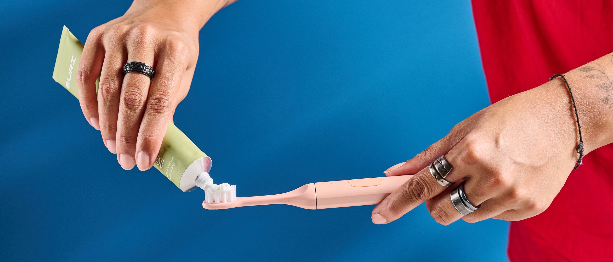 the Suri 2.0 toothbrush in sunset bloom pink colorway with a plant-based head and aluminum body, pictured with its uv cleaning travel case and the suri toothpaste