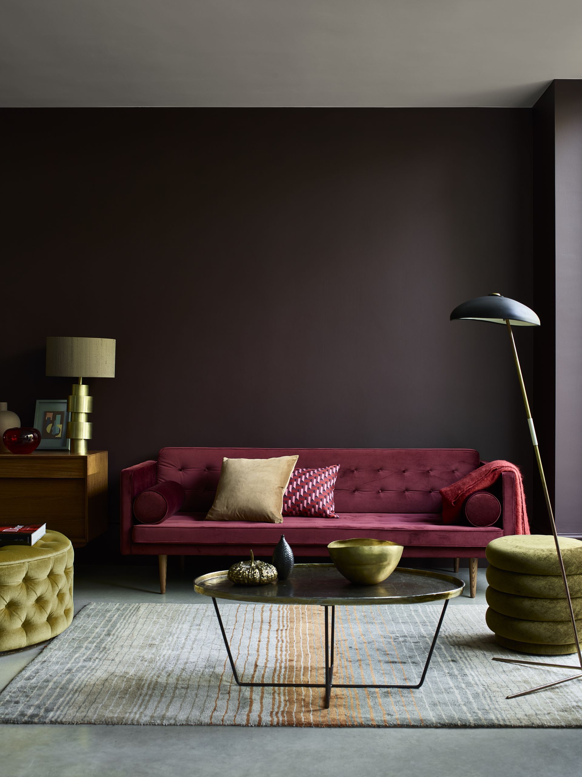 Ideas for living room paint colors shown in a dark chocolate brown, with a plum colored velvet sofa, green velvet pouffes and metal accents.