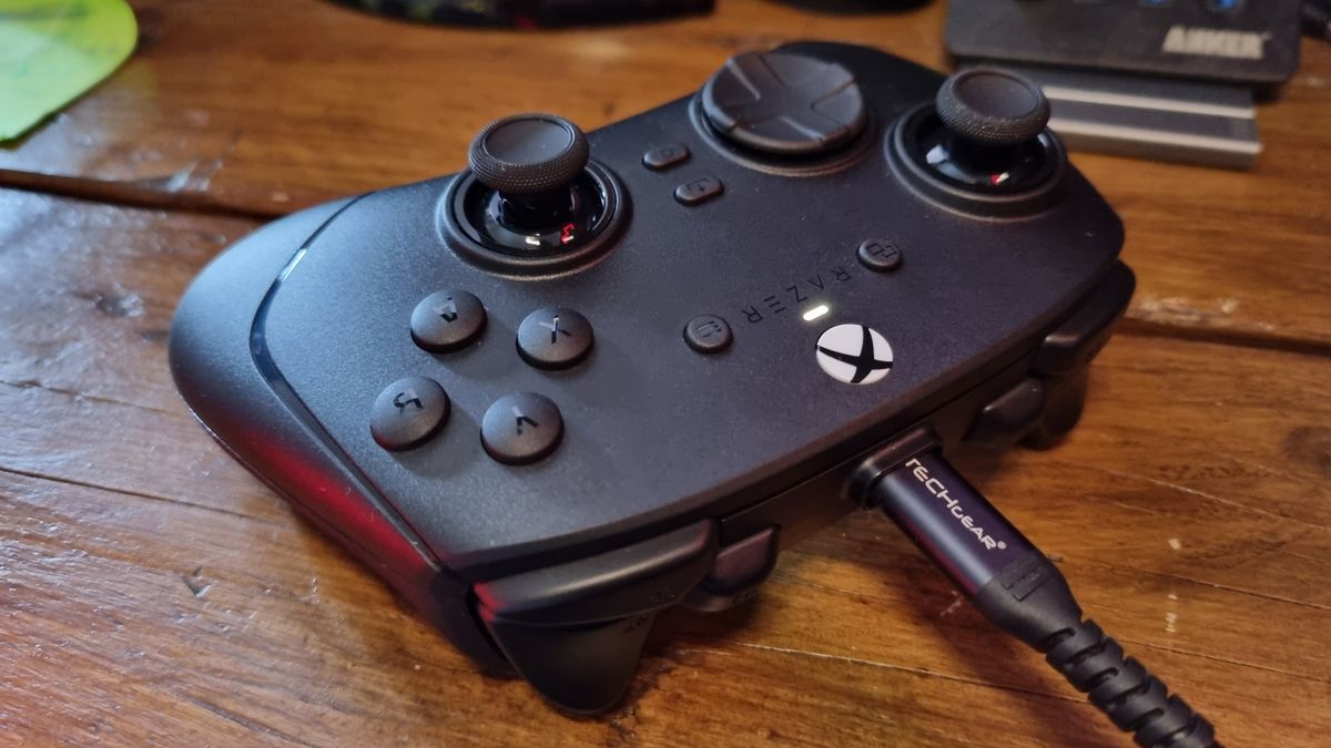 A Razer Wolverine V4 Pro connected to a charging cable, on a desk