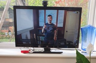 A smiling person on a TV screen showing thumbs up