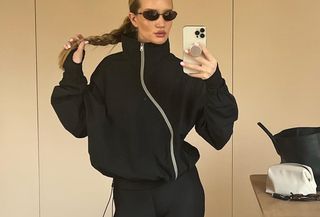 Model Rosie Huntington-Whiteley wears black anorak and black leggings while taking mirror selfie.