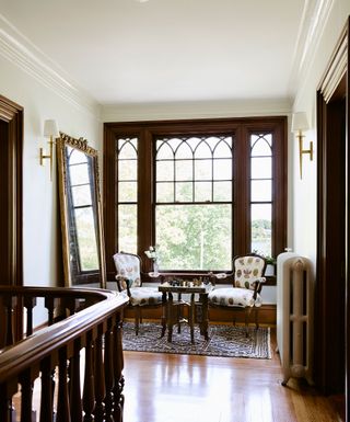landing with gothic style period windows big mirror and carver chairs with chess set on table and banisters