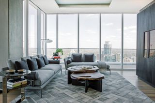 The Independent Penthouse by Urbanspace Interiors - two sofas with a backdrop of floor to ceiling windows overlooking a city.