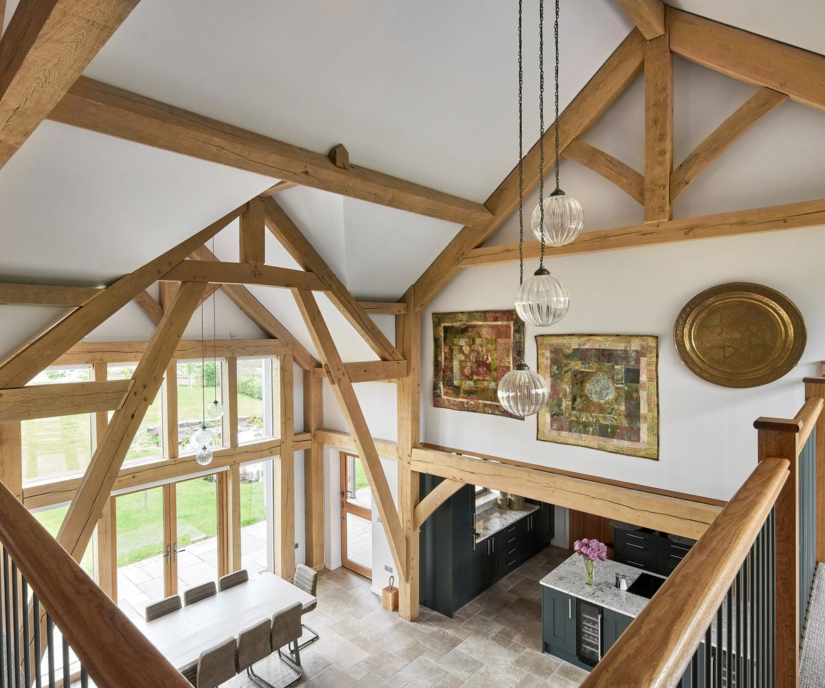 A double heigh atrium in an oak frame self-build. There are lots of exposed beams and natural light coming from a double-height feature window