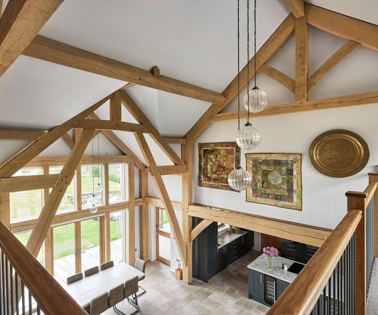 A double heigh atrium in an oak frame self-build. There are lots of exposed beams and natural light coming from a double-height feature window
