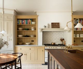 white and butter yellow kitchen with a traditional white and gold range cooker framed by butter yellow shelves ad cabinetry