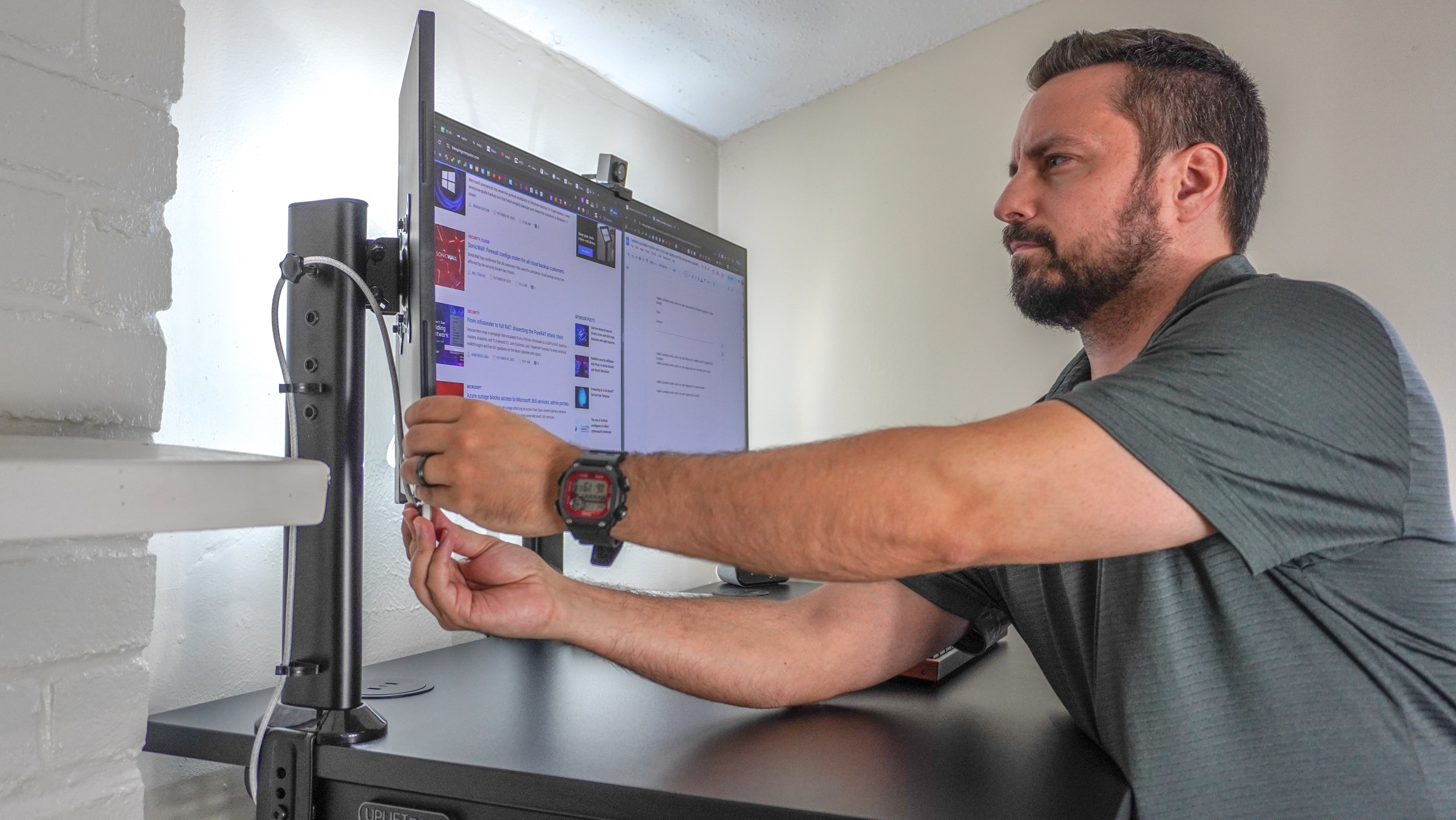 A person connecting a portable monitor mounted next to an ultrawide display