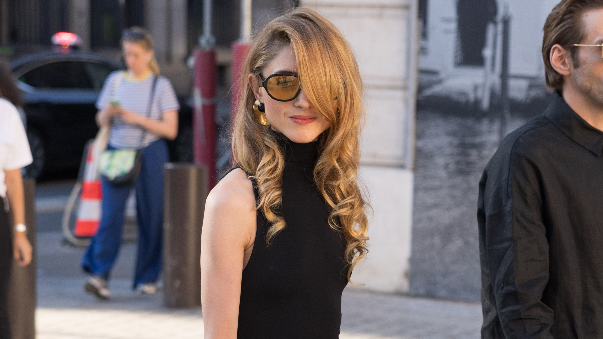 a woman with light brown hair and a black sleeveless top