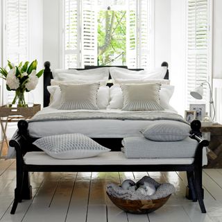 bedroom with white bedding and bench with pillows