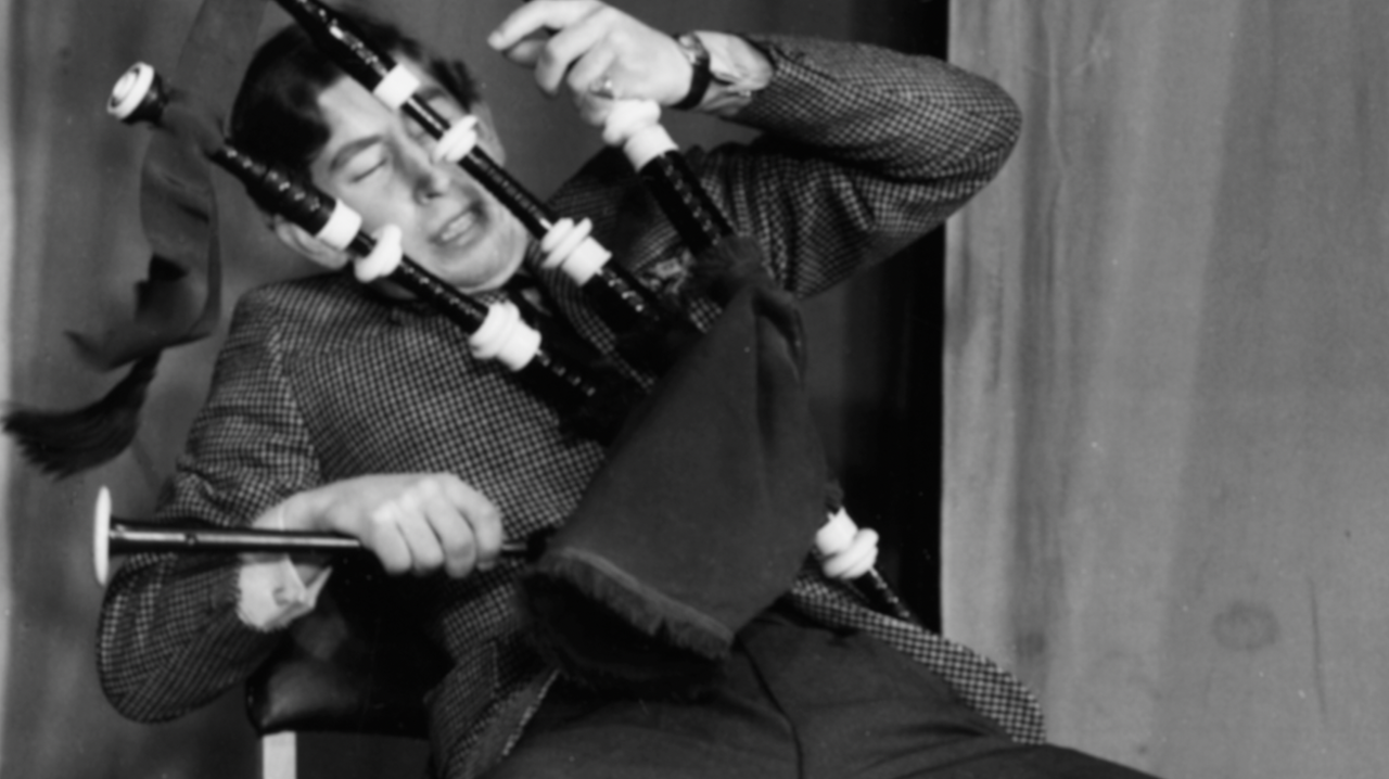 Prince Charles, the Prince of Wales, joking around with a set of bagpipes as he appears on stage in a student revue in &#039;Quiet Flows the Don&#039;, at Trinity College, Cambridge University, February 23rd 1970