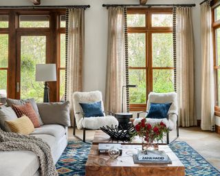 Living room with gray sofa and sheepskin armchairs, blue patterned rug and coffee table