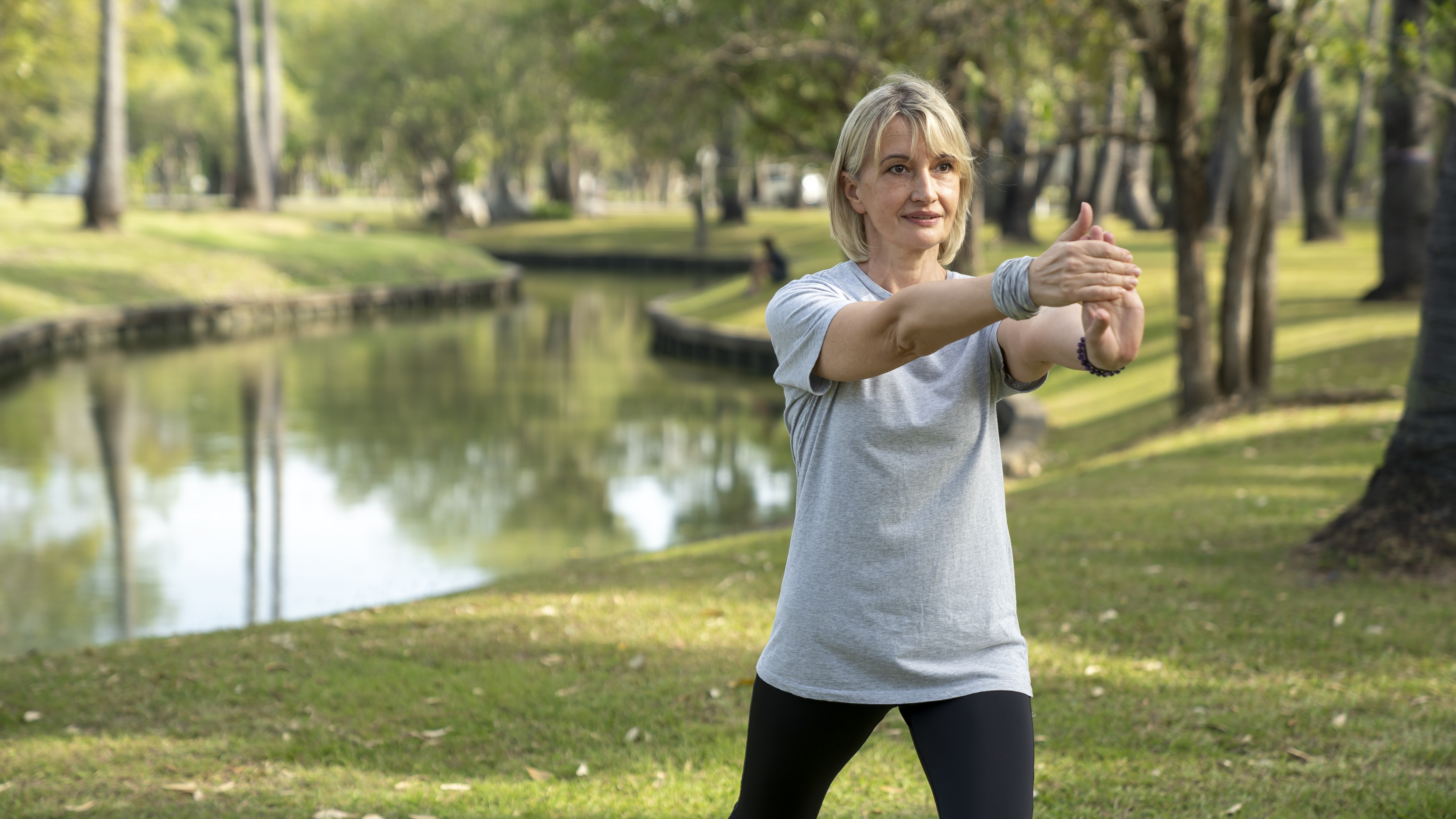A mature menopausal woman practices Tai Chi outdoors.