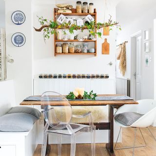 white kitchen with banquette seating and table with spice jars on a shelf