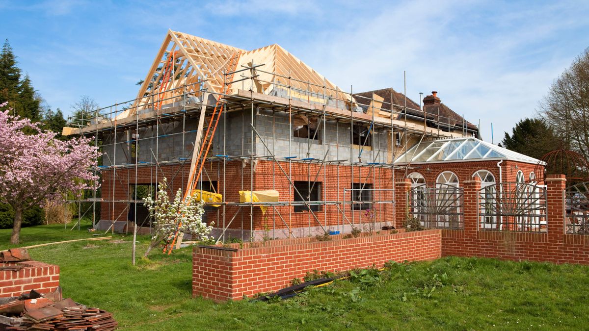 Two storey brick-clad house being built on a large side garden 