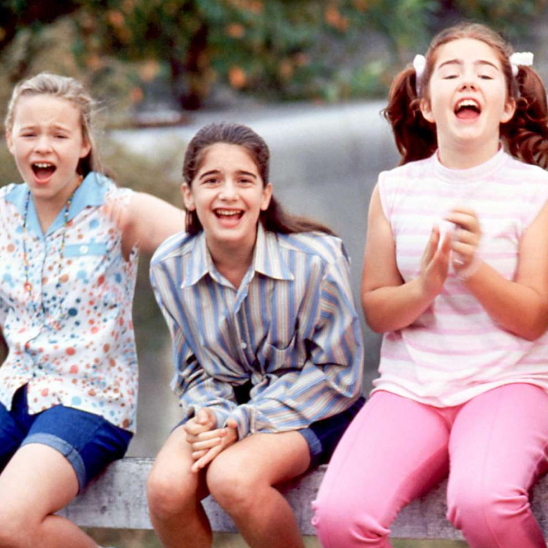 three girls sitting on a fence screaming in a still from the movie now and then