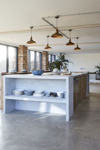 A bright kitchen with an island with storage containing bowls in the middle of the room