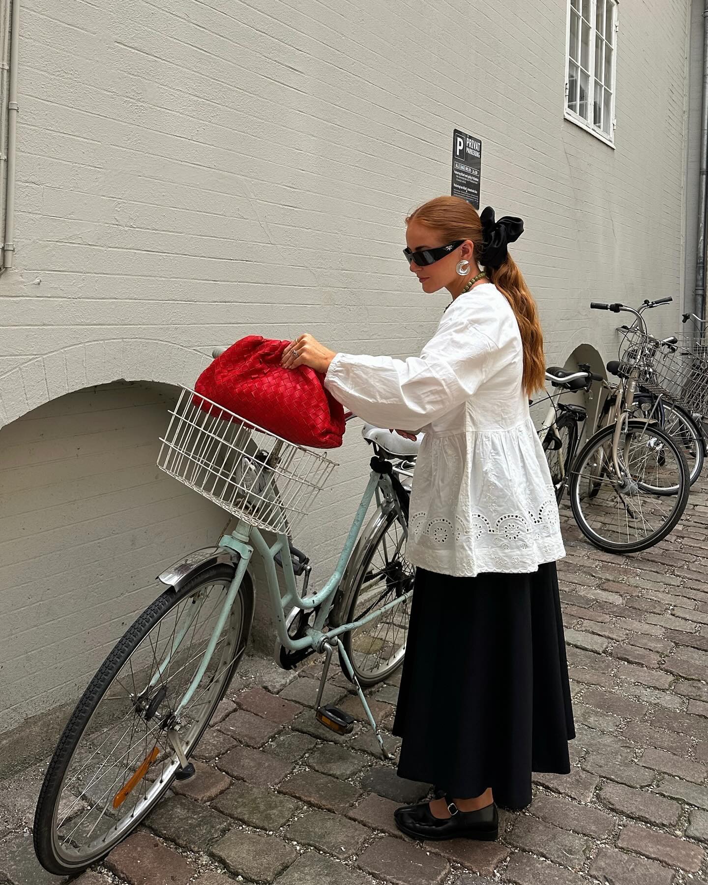 @rebeccaferrazwyatt wears a white top, black skirt and red bag