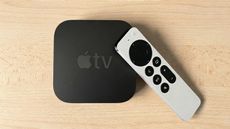 Apple TV 4K sitting on wooden desktop (shown from above)
