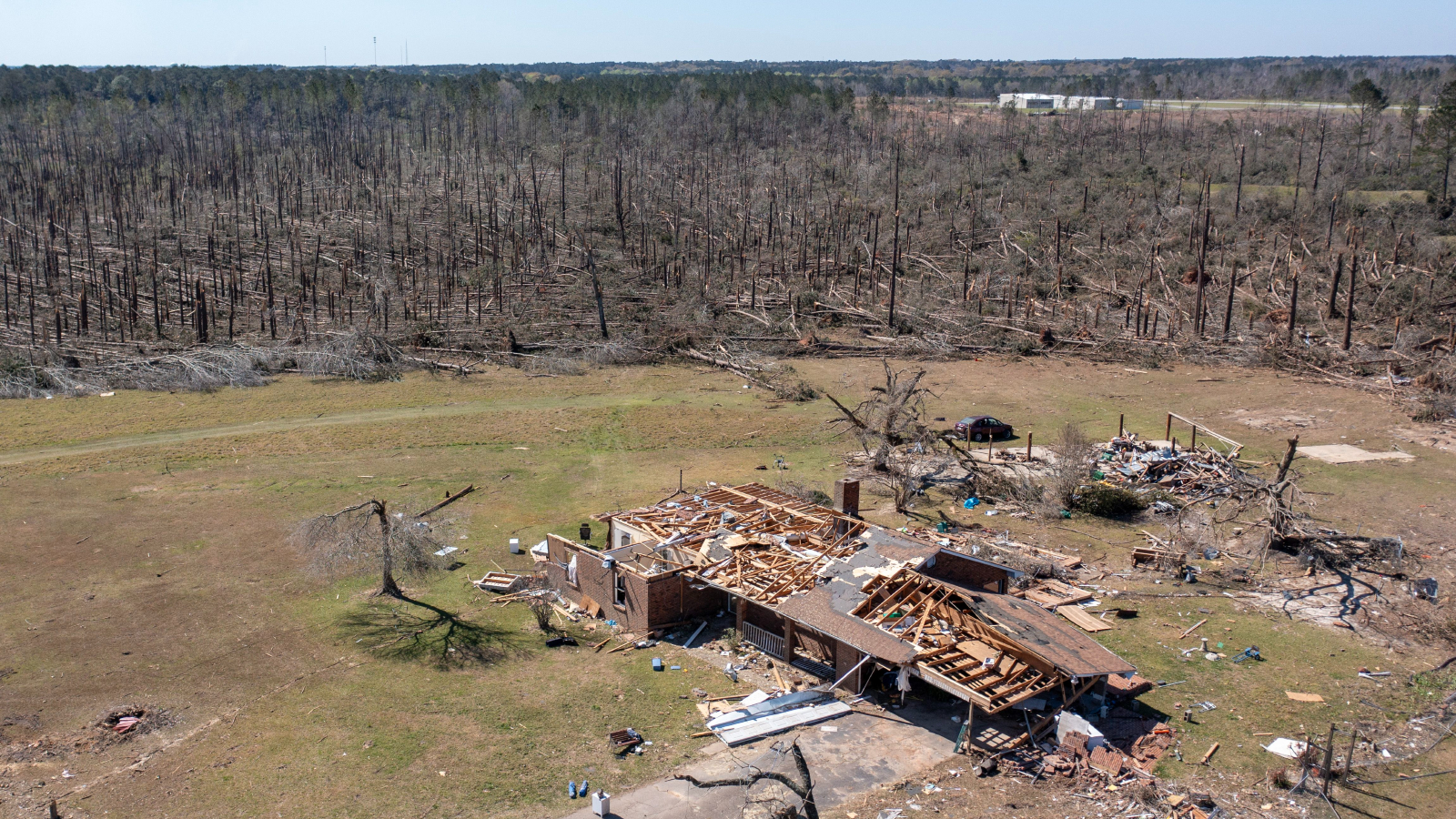 An aerial photograph showing a wrecked house surrounded by uprooted trees
