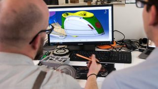 Two office workers using CAD software to design vehicle