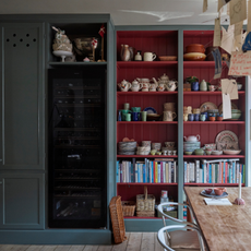 a green and red painted kitchen with built in shelving and large wine fridge 