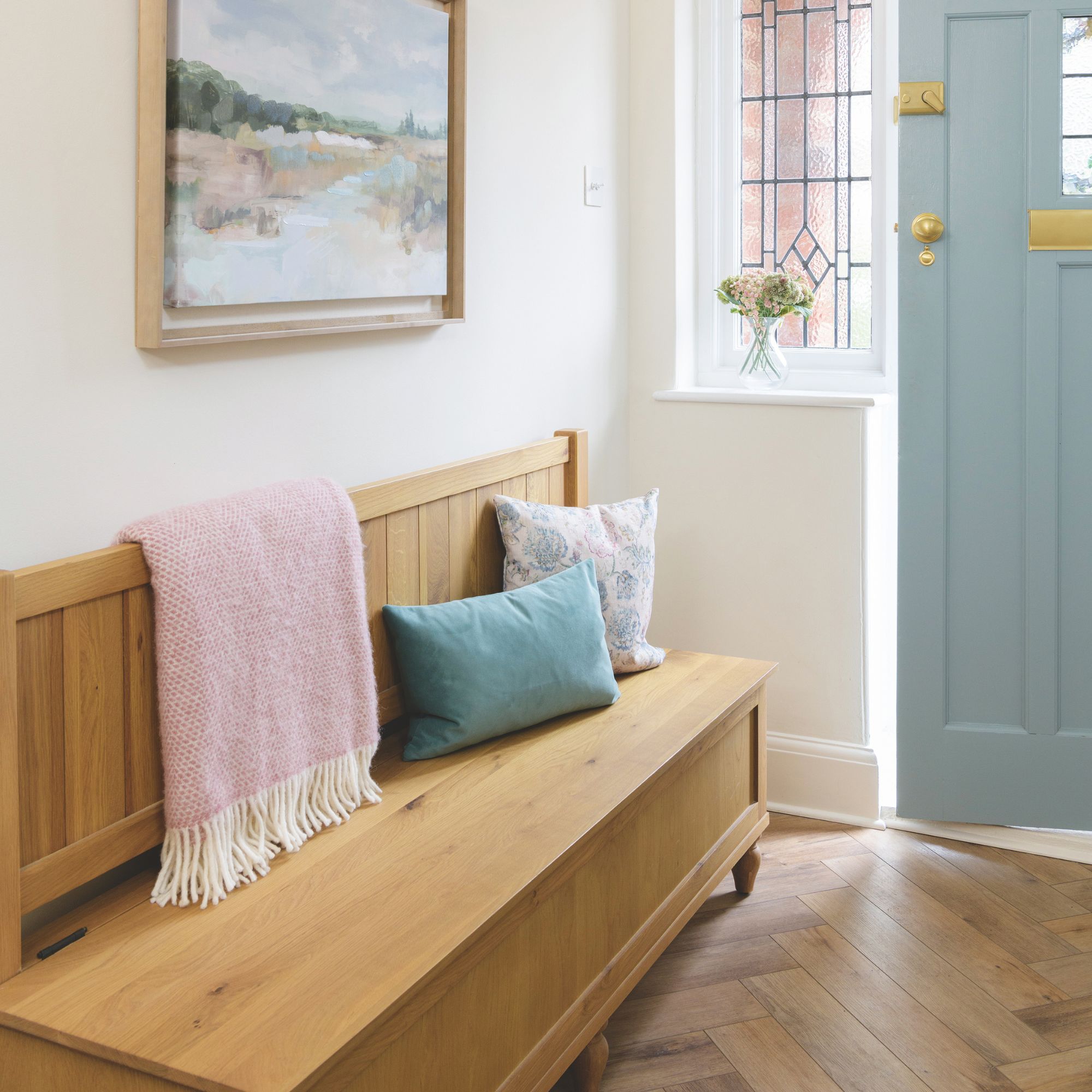 Cottage style entryway with wooden flooring, a blue front door and a wooden storage bench