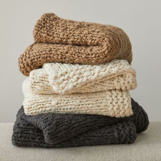 West Elm Wool Knit Throw in beige, cream and dark grey colors, folded in a stack