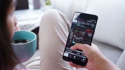 A woman looks at the top investment funds' performance on her mobile phone