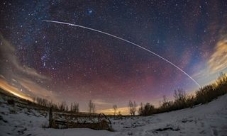 A pass of the International Space Station on the evening of January 26, 2019. The ISS is moving from right to left, southwest to southeast. The ISS faded and reddened naturally into sunset at top left in Taurus. Just before it did that it passed through the Hyades star cluster and just missed Aldebaran. The ISS seemed to track along the ecliptic here, made somewhat visible by the faint arc of the zodiacal light reaching up from the horizon at right and stretching across the sky to the upper left. The ISS coincidentally travelled parallel to, but just below the zodiacal light, which follows the ecliptic. Some red streaks of airglow are also visible, and I emphasized those in the colour correction to make a more colourful sky. I did the opposite to the light polluted clouds! But their yellow remains.