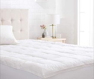 Amazon Basics Mattress Protector on a bed against a white wall,