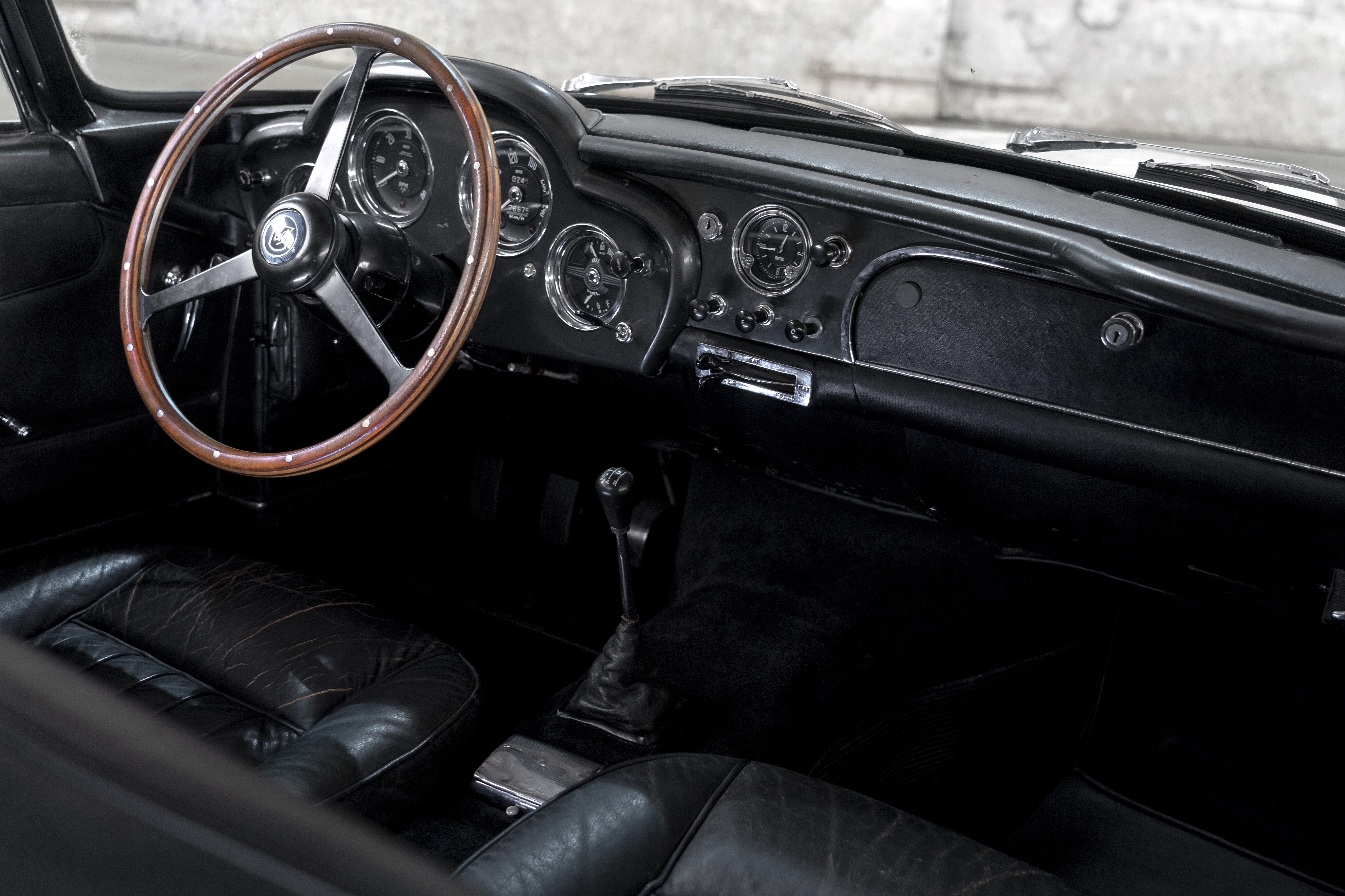 Details of the Aston Martin DB4, painted white, in a grey airplane hangar