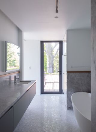 A minimalist bathroom with mosaic floor tiles and marble vanity