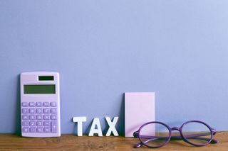 the word tax next to eye glasses, a calculator and note pad
