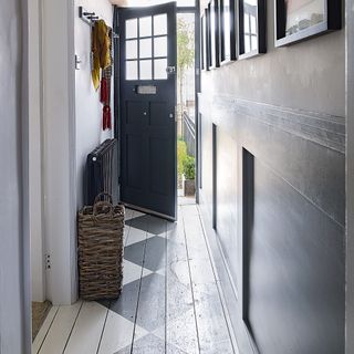 White hallway with dark grey panelling and front door, and hallway painted with stencils