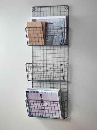 A three tier wall mounted magazine rack made with black wire mesh