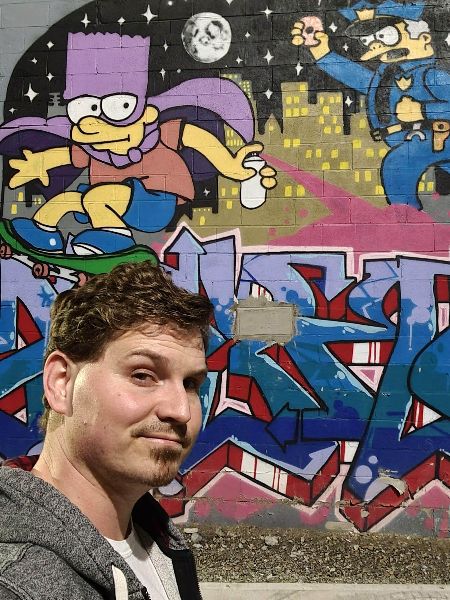 Selfie taken with the Galaxy S21 FE next to a wall of graffiti