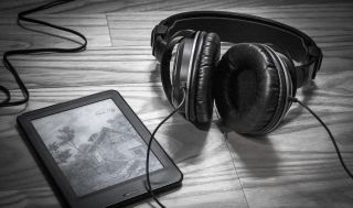 An ebook reader on table with a headset.