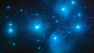 A cluster of bright blue stars that make up the Pleiades in the constellation Taurus
