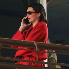 Kendall Jenner walking and talking on the phone while wearing a red cashmere robe by The row and Hailey Bieber's favorite ballet flats