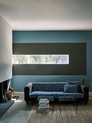 Modern, blue living room with a thin, long rectangular window that is outlined in an olive green boarder.