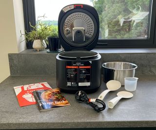 The parts of the Cosori 5-Quart Rice Cooker on a gray kitchen countertop