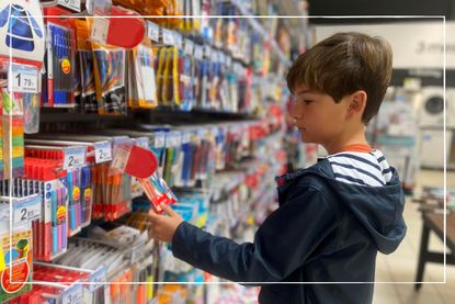 Child looking at school supplies, including pends and pencils, in a shop