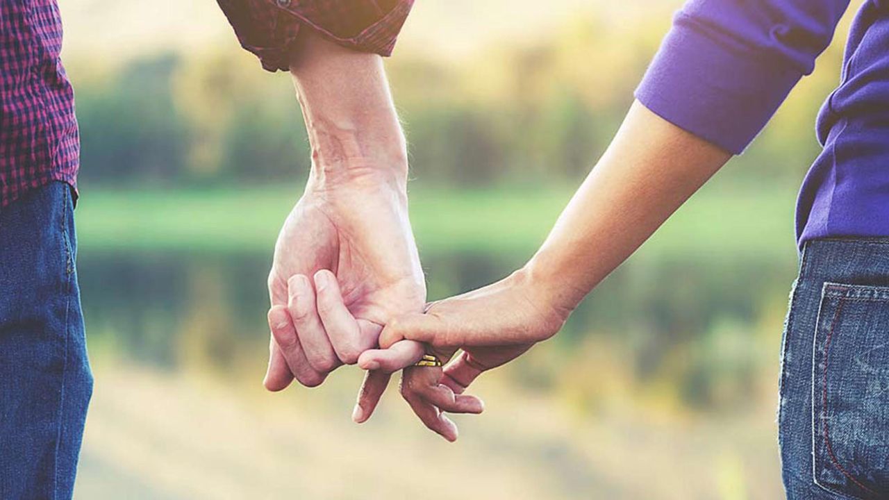 A couple link their pinky fingers together.