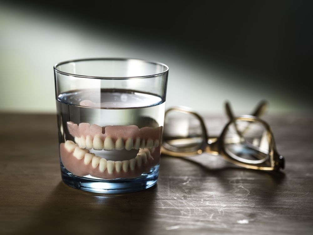 Still photograph of dentures in a glass of water.